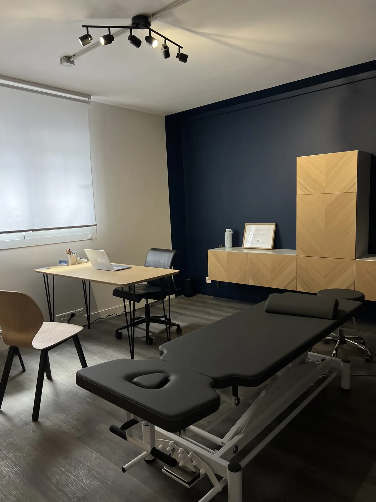 Cabinet d'ostéopathie de Victoire Thomas à Asnières-sur-Seine : bureau de consultation, table de soin et mur bleu nuit
